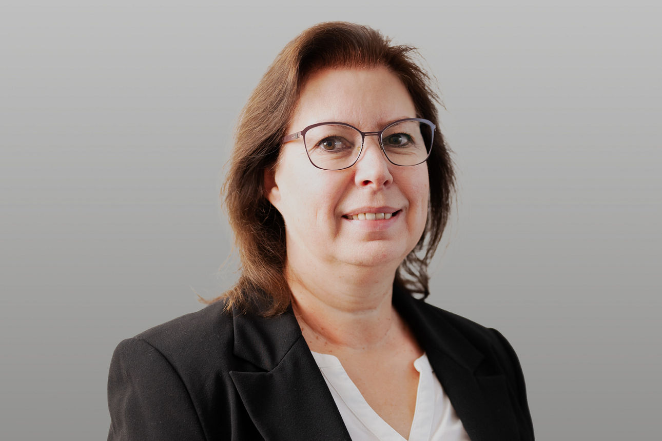 Servicemitarbeiterin Susanne Saam vor grauen Hintergrund