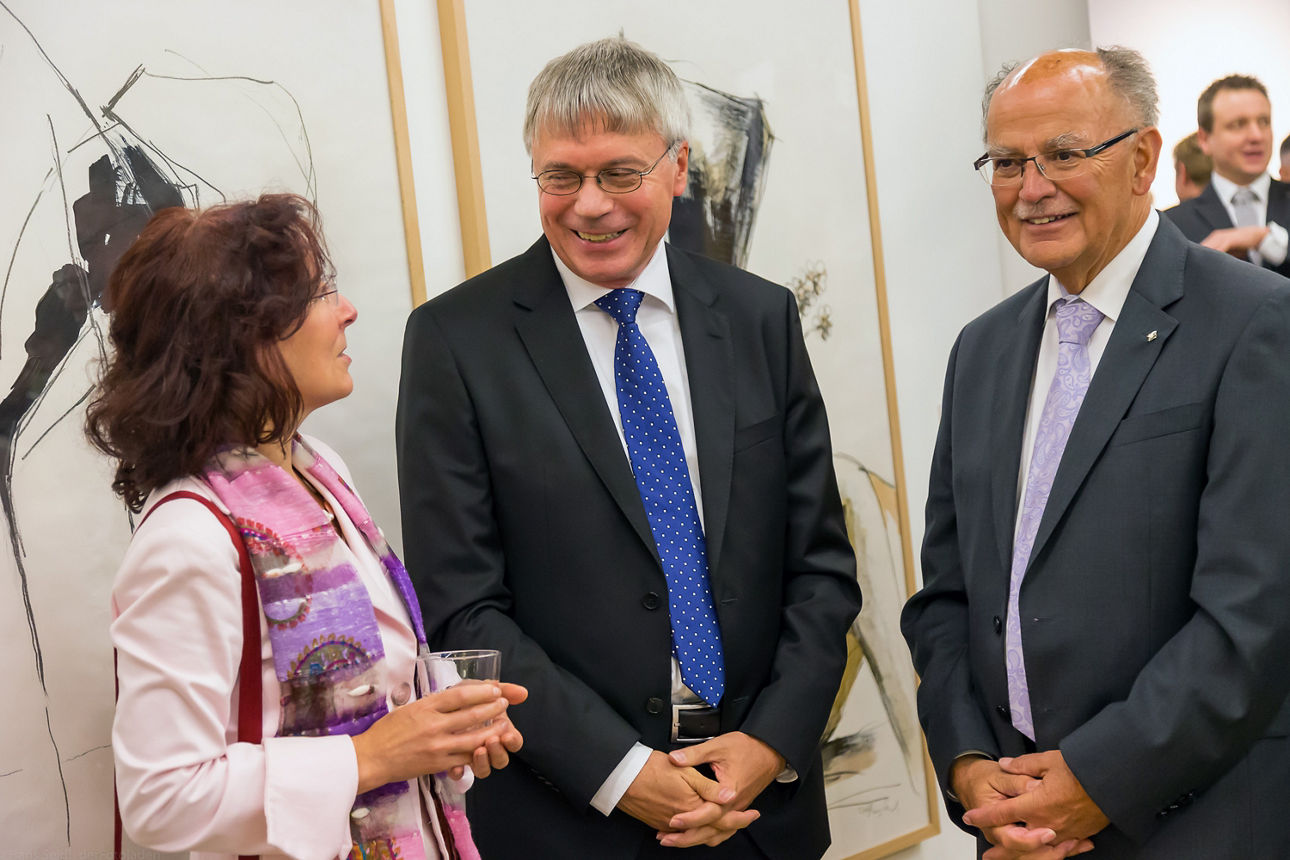 Zwei Männer und eine Frau unterhalten sich auf einer Kunstausstellung