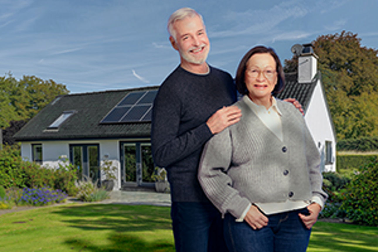 Älteres Paar vor ihrem saniertem Eigenheim