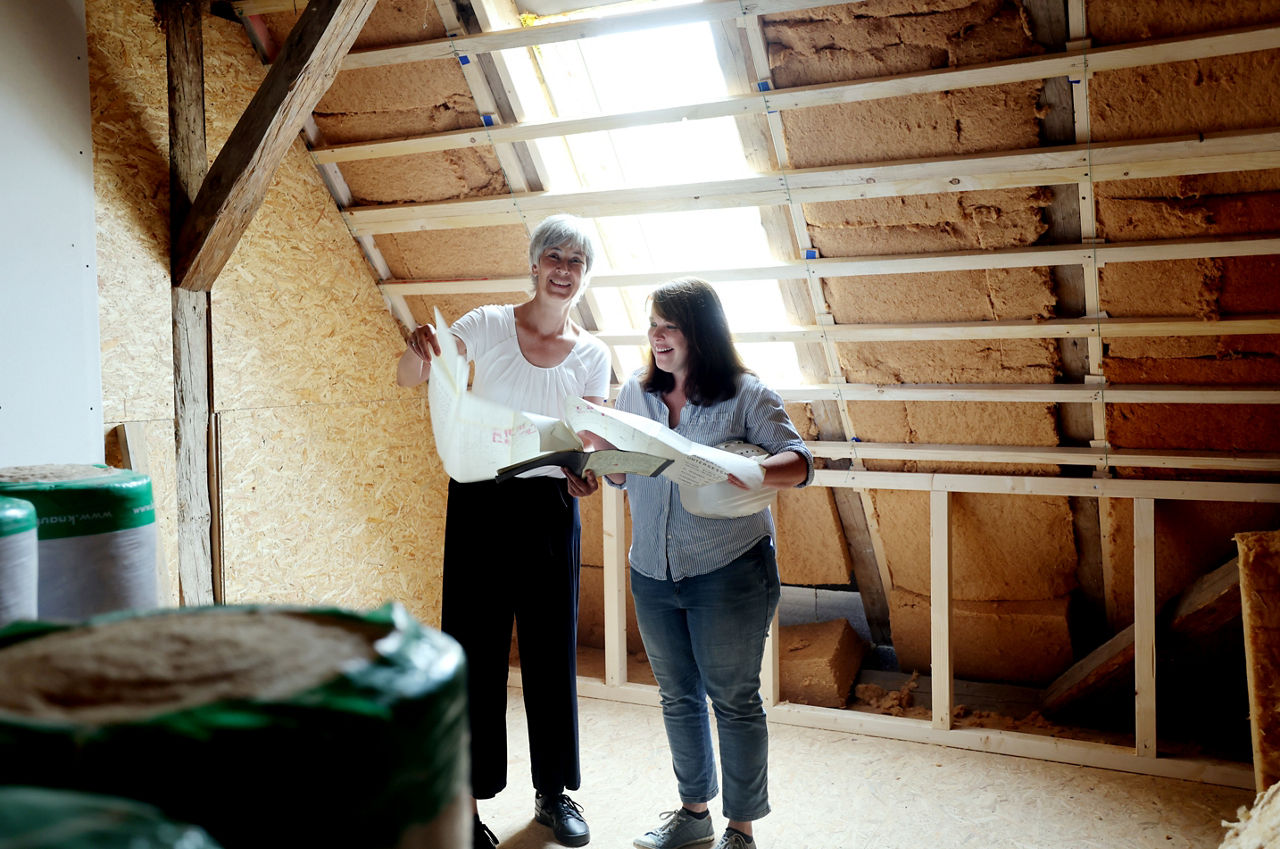 Zwei Frauen stehen auf einer Baustelle und schauen auf einen Bauplan
