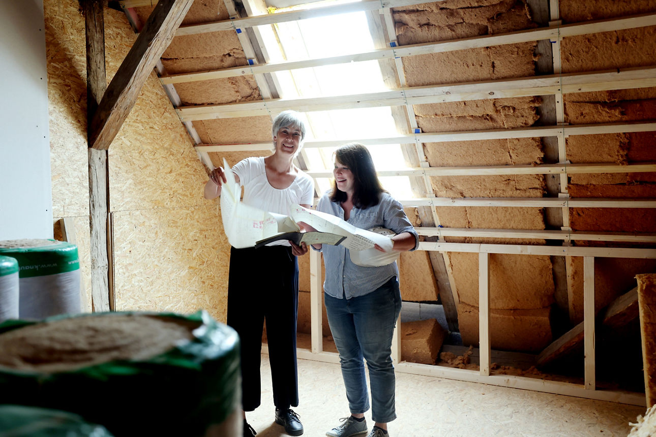 Zwei Frauen stehen auf einer Baustelle und schauen auf einen Bauplan