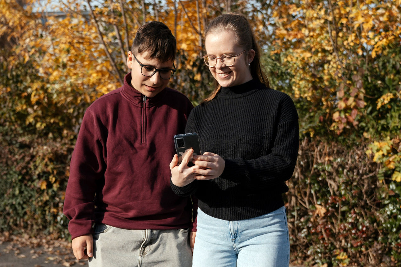 Schülerin zeigt Schüler ubiMaster-App auf dem Smartphone