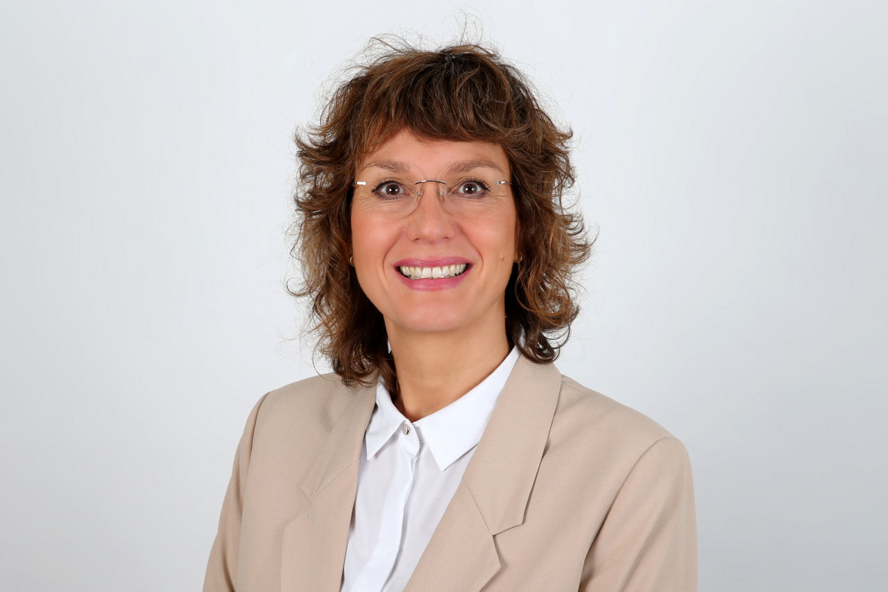 Eine lächelnder Frau schaut in die Kamera.