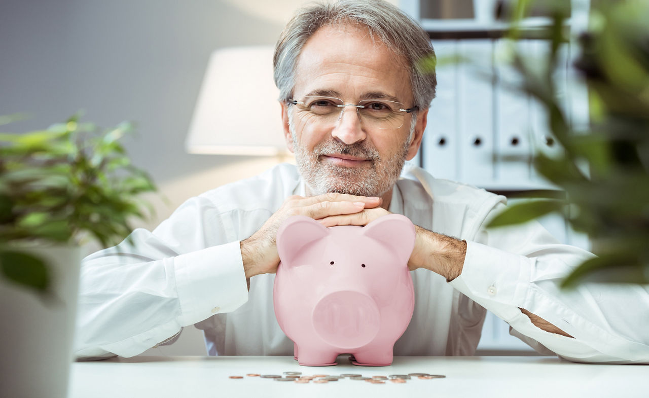 Erwachsener Mann mit Sparschwein. Konzept des verantwortungsvollen Investierens.