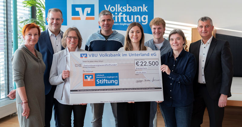 Gruppe von Personen halten den Scheck der Sependenübergabe vor sich