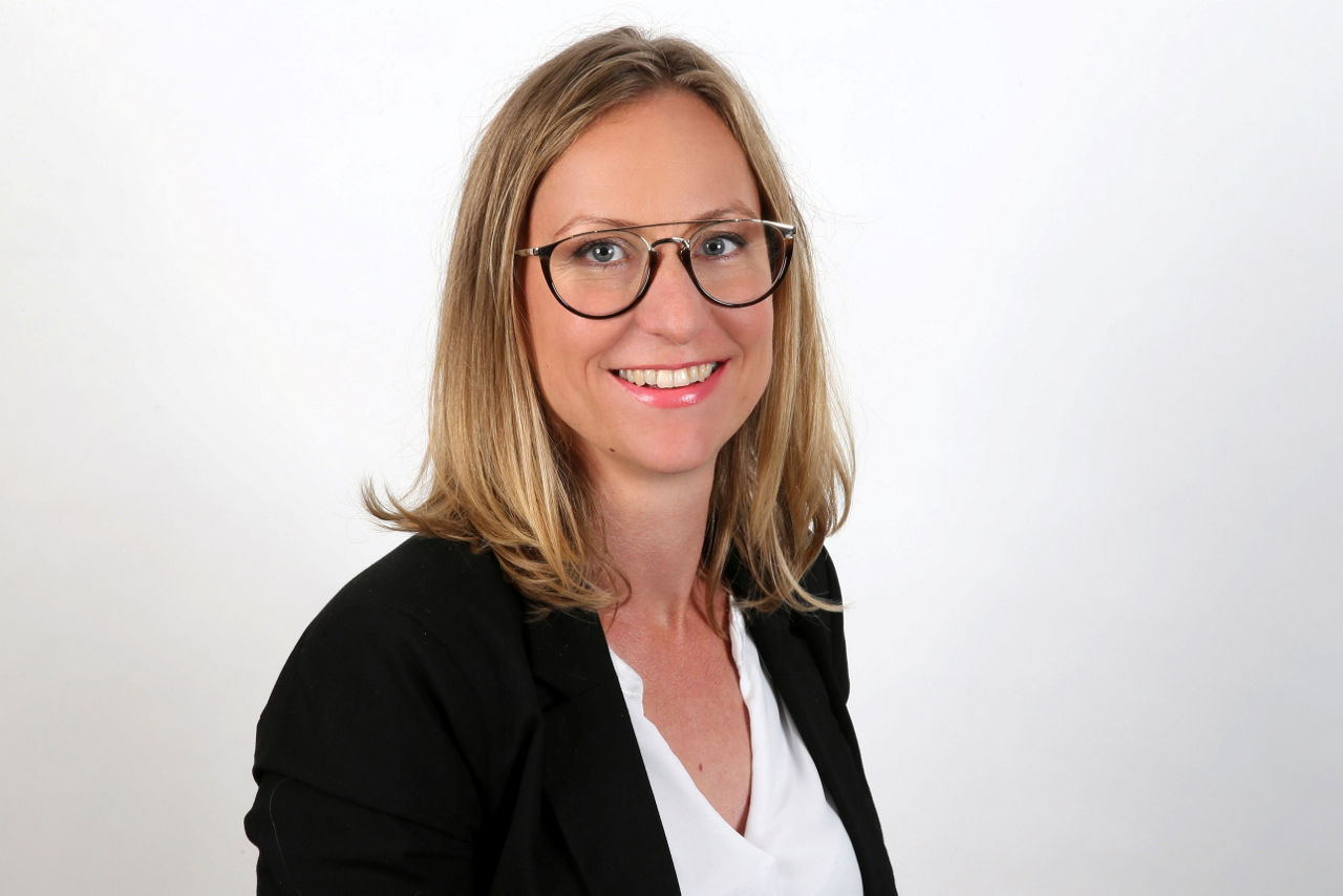 Eine lächelnder Frau schaut in die Kamera.