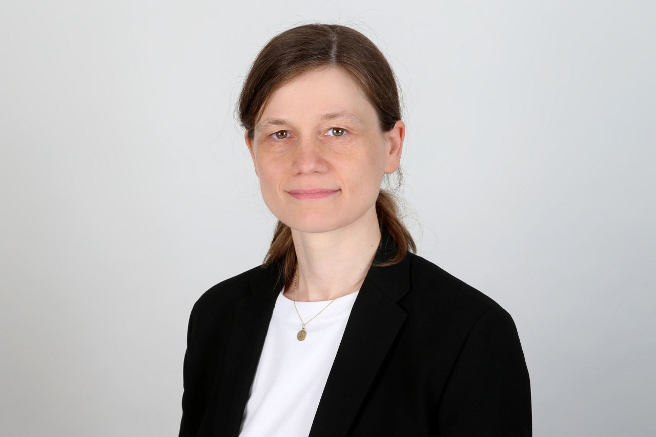Eine lächelnder Frau schaut in die Kamera.