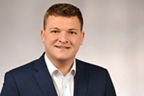 Mitarbeiter David Schneider trägt einen Anzug und hat kurze blonde Haare