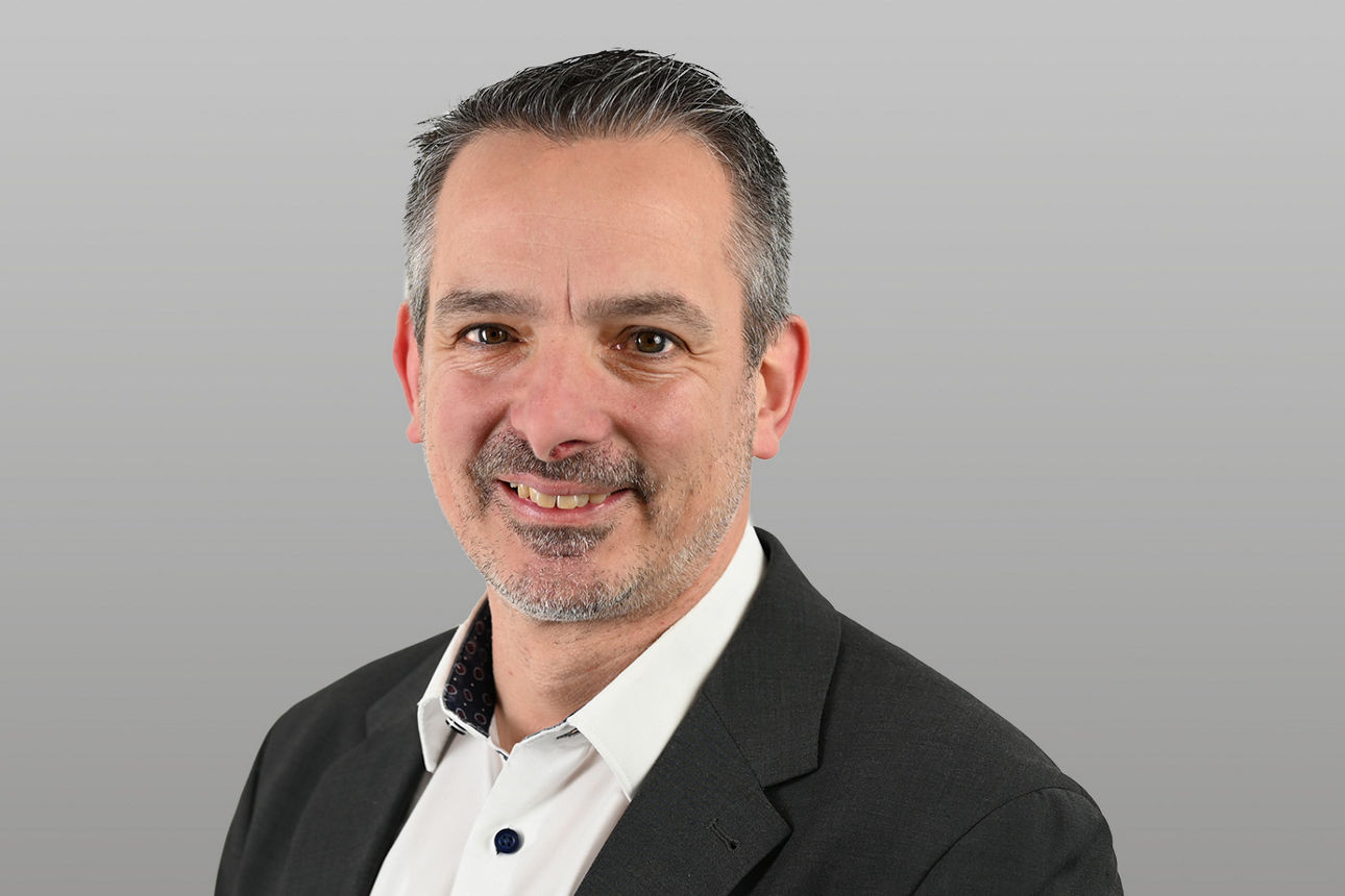 Michael Schneider, Gewerbe- u. Firmenkundenberater, vor grauem Hintergrund