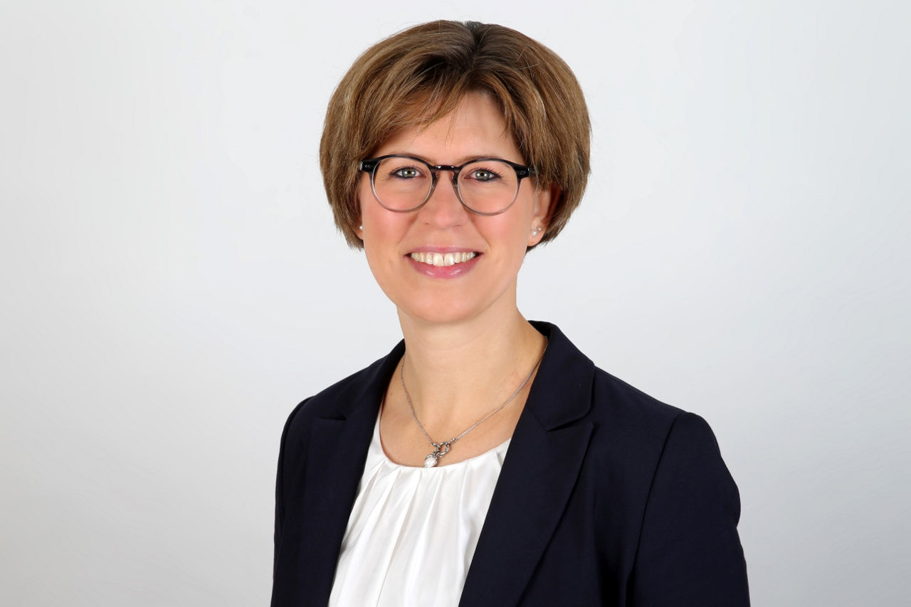 Eine lächelnder Frau schaut in die Kamera.