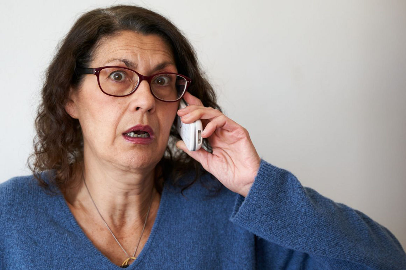 Eine Frau am Telefon und entsetztem Gesicht