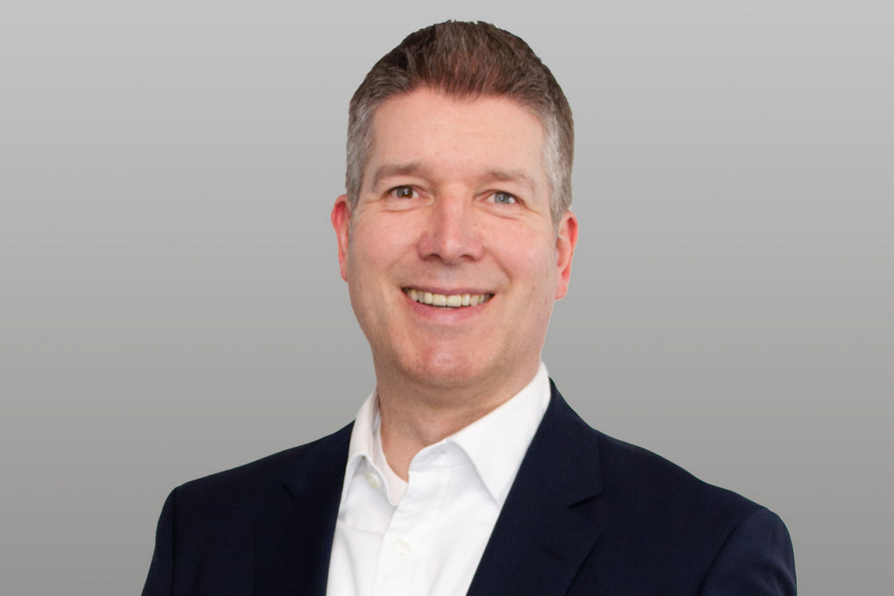 R+V Versicherung Unternehmenskundenberater Komposit Marc Schrandt vor grauem Hintergrund