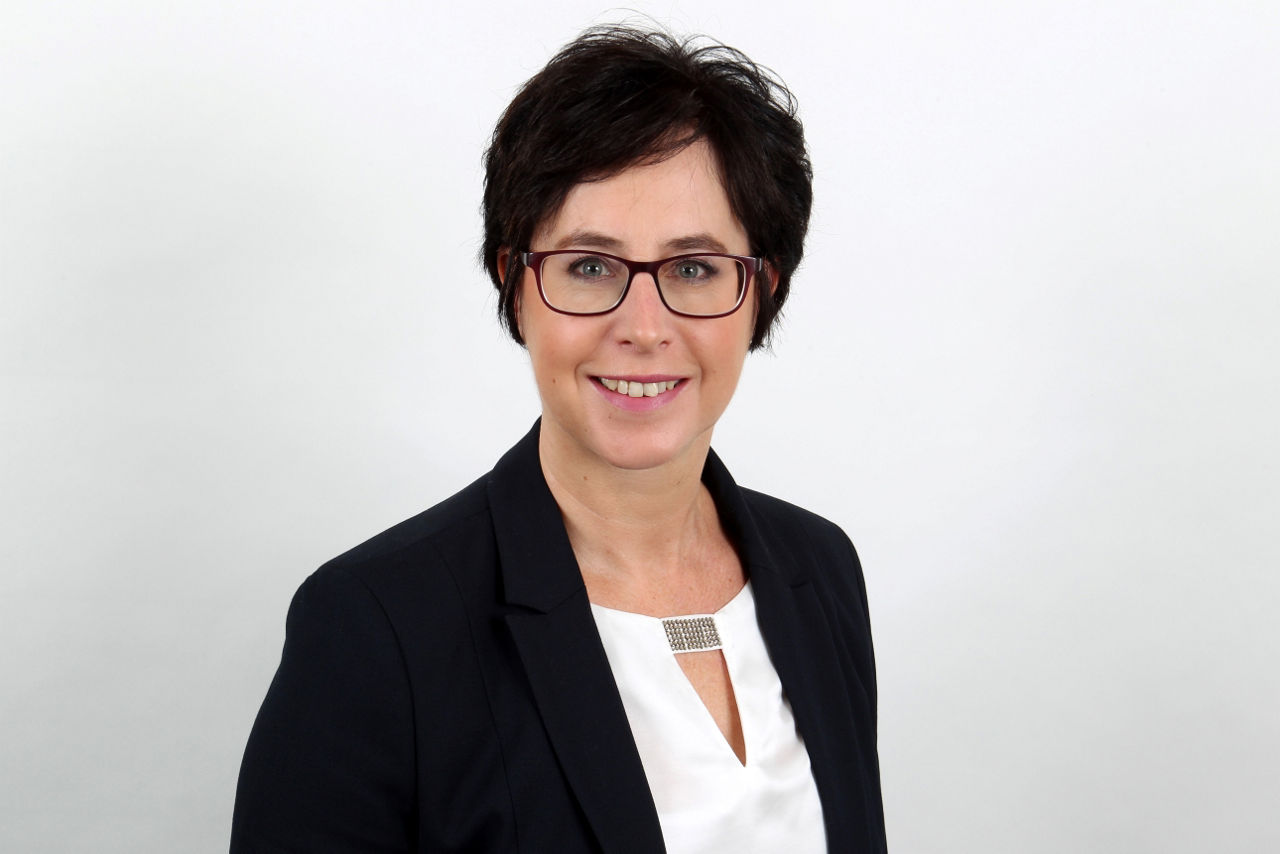Eine lächelnder Frau schaut in die Kamera.