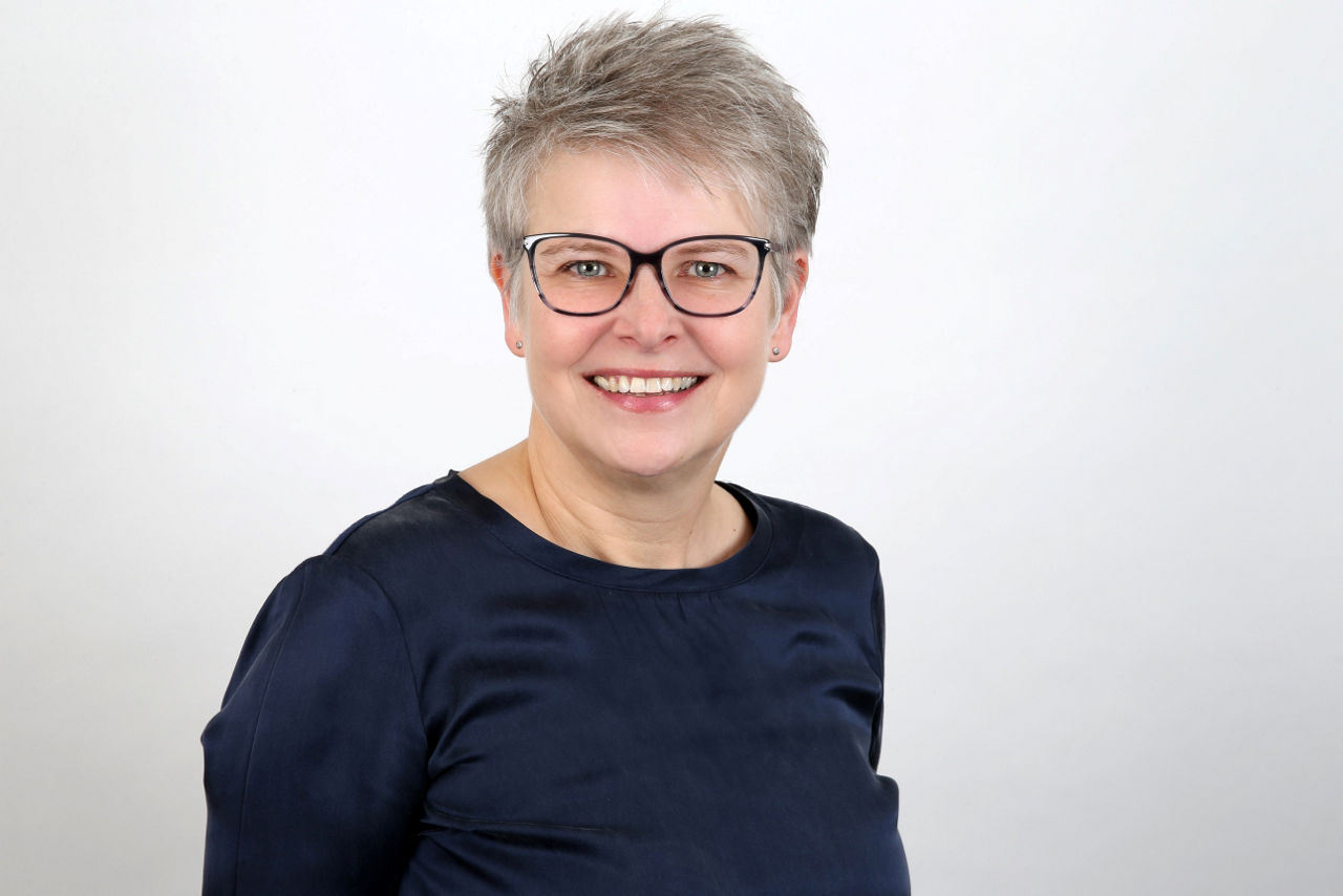 Eine lächelnde Frau schaut in die Kamera.
