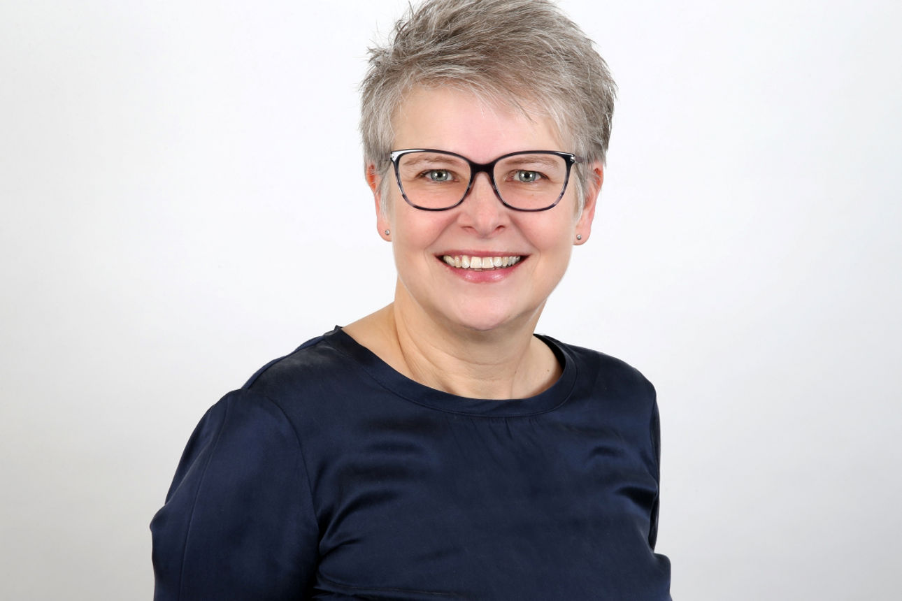 Eine lächelnde Frau schaut in die Kamera.