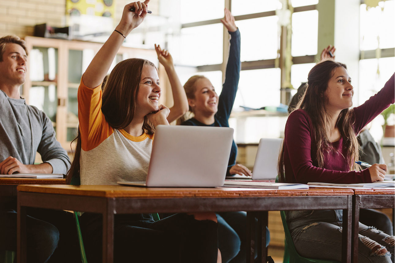 Schülerinnen und Schüler sitzen in der Klasse und melden sich.