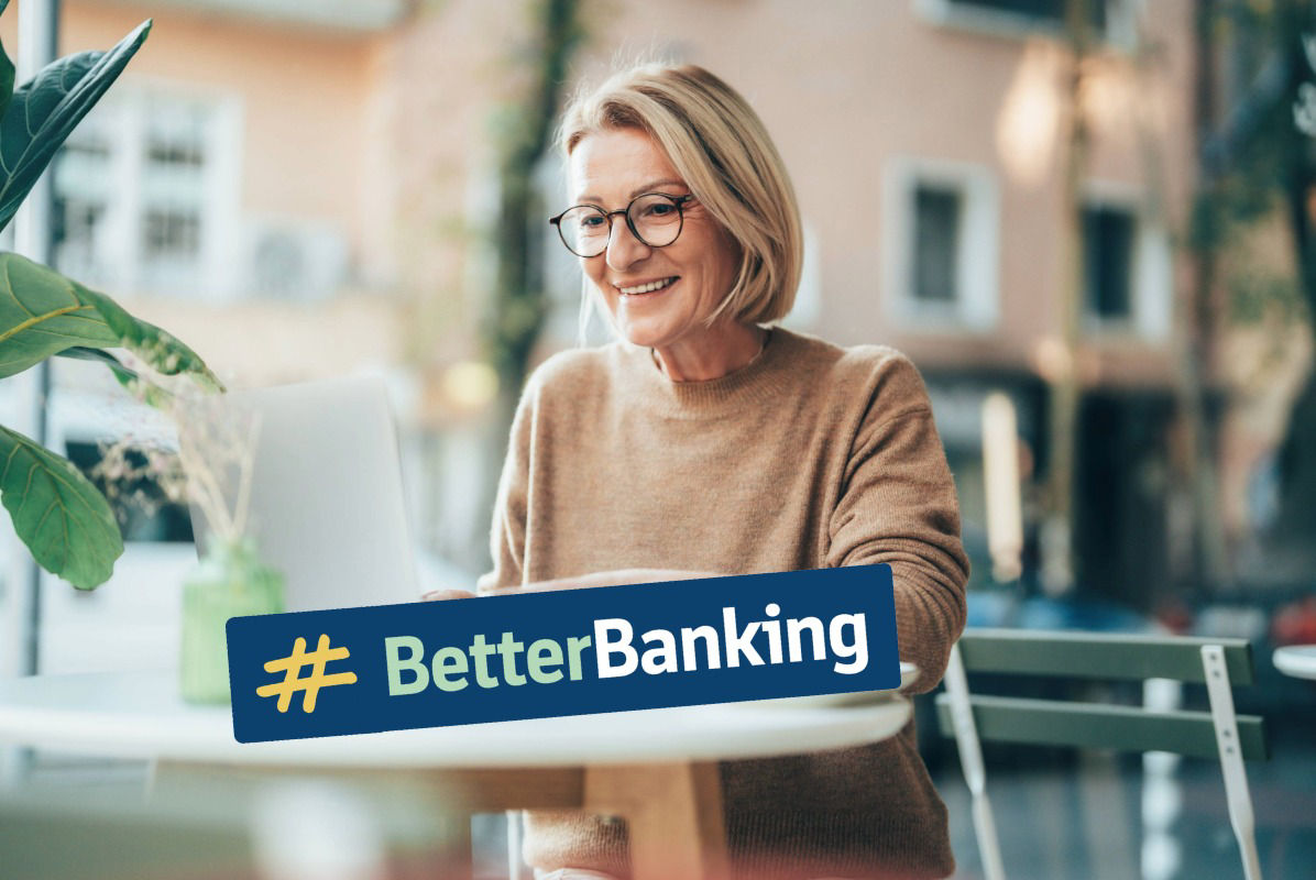 Frau mittleren Alters sitzt im Café und schaut auf Bildschirm ihres Laptops