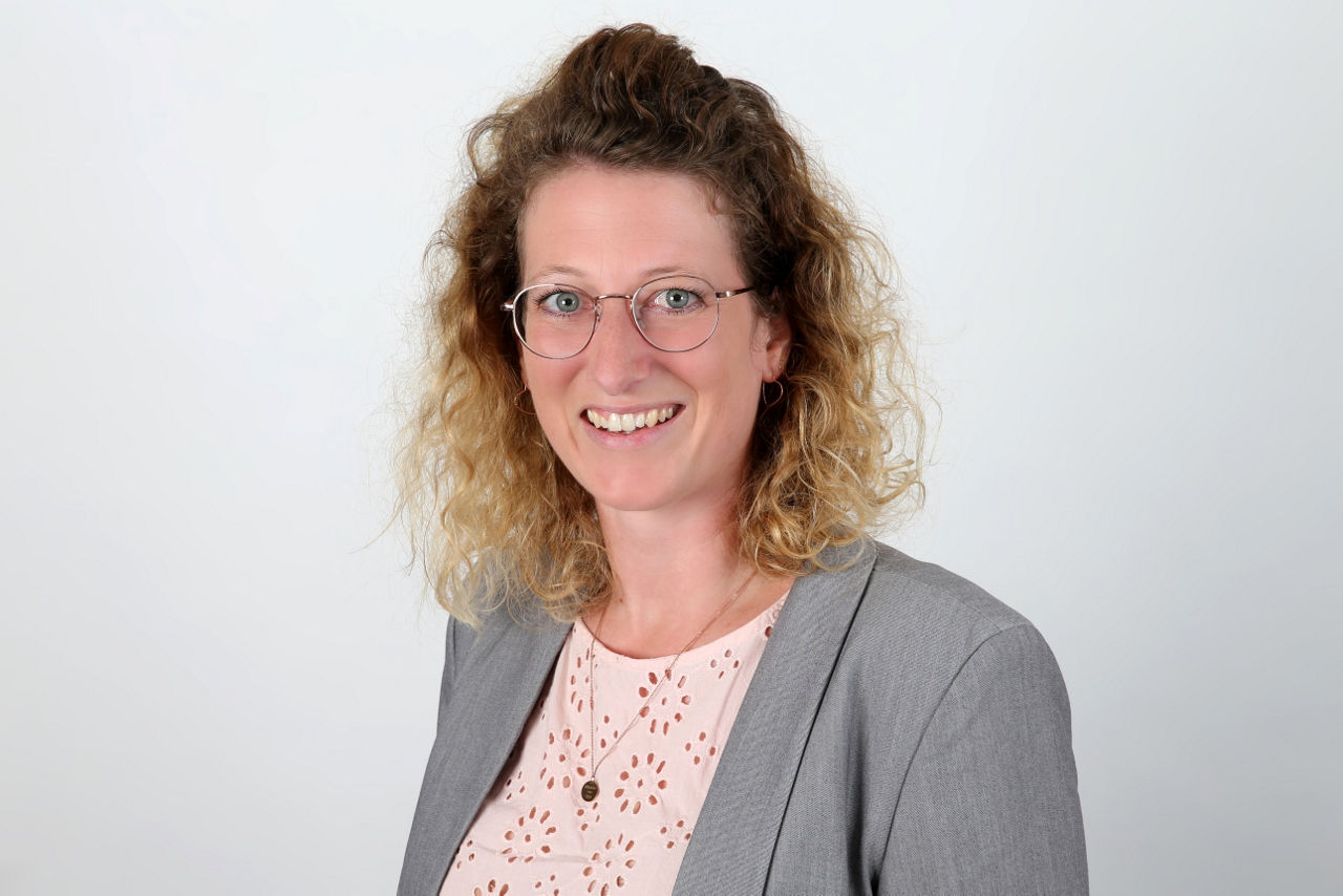 Eine lächelnder Frau schaut in die Kamera.