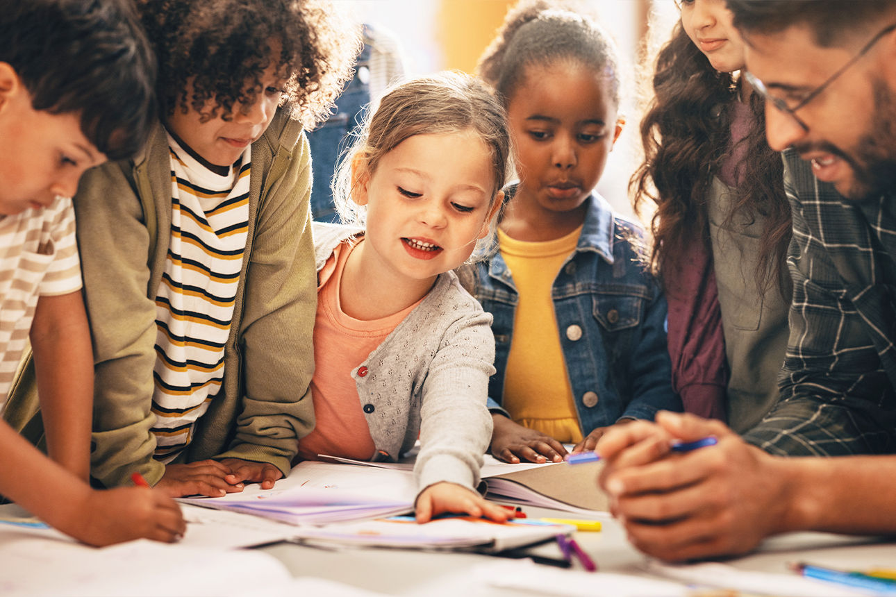 Kinder und ein Lehrer malen gemeinsam