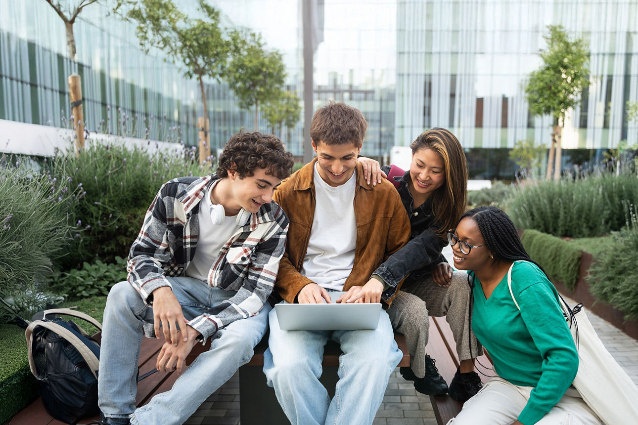 Gruppe junger Menschen am Laptop auf dem Campus