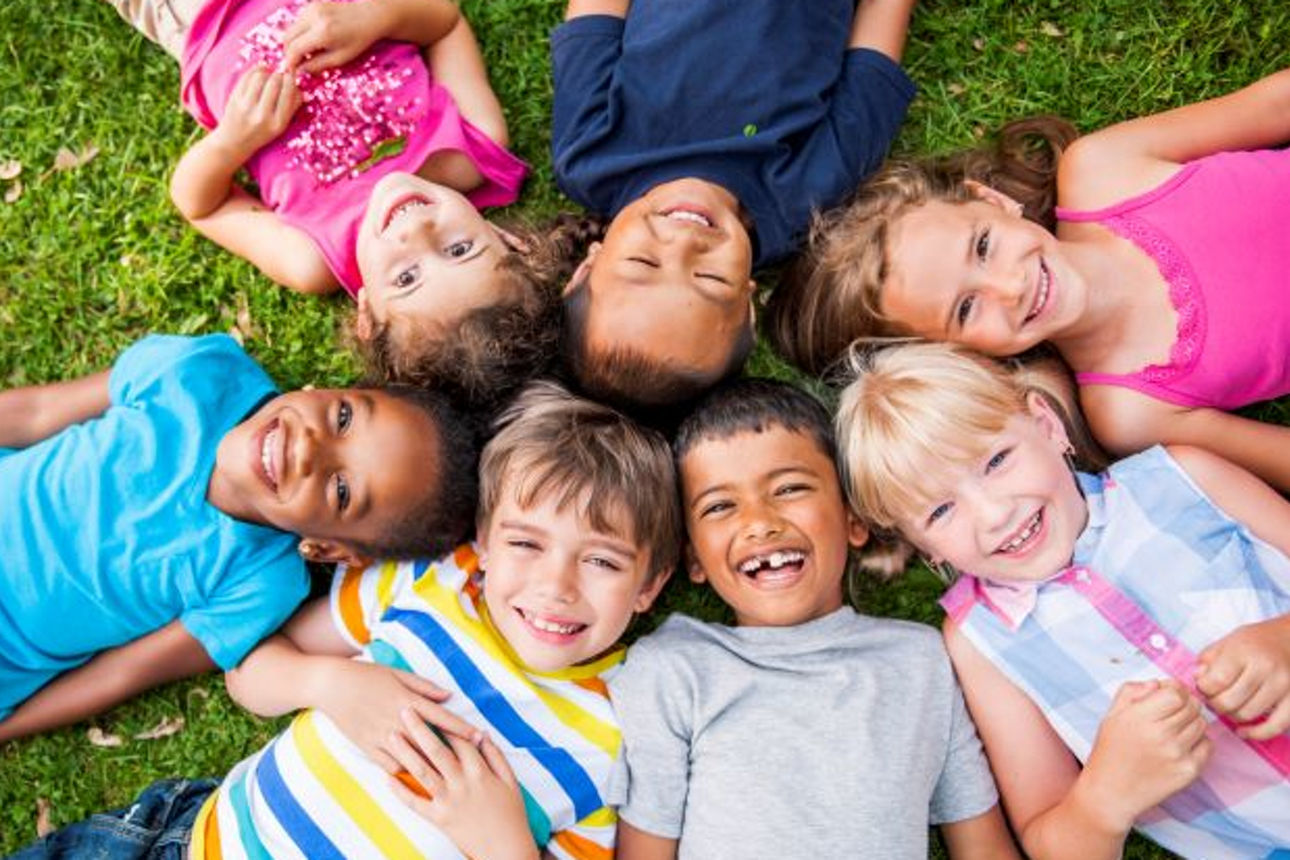 Kinder liegen im Kreis mit den Köpfen aneinander