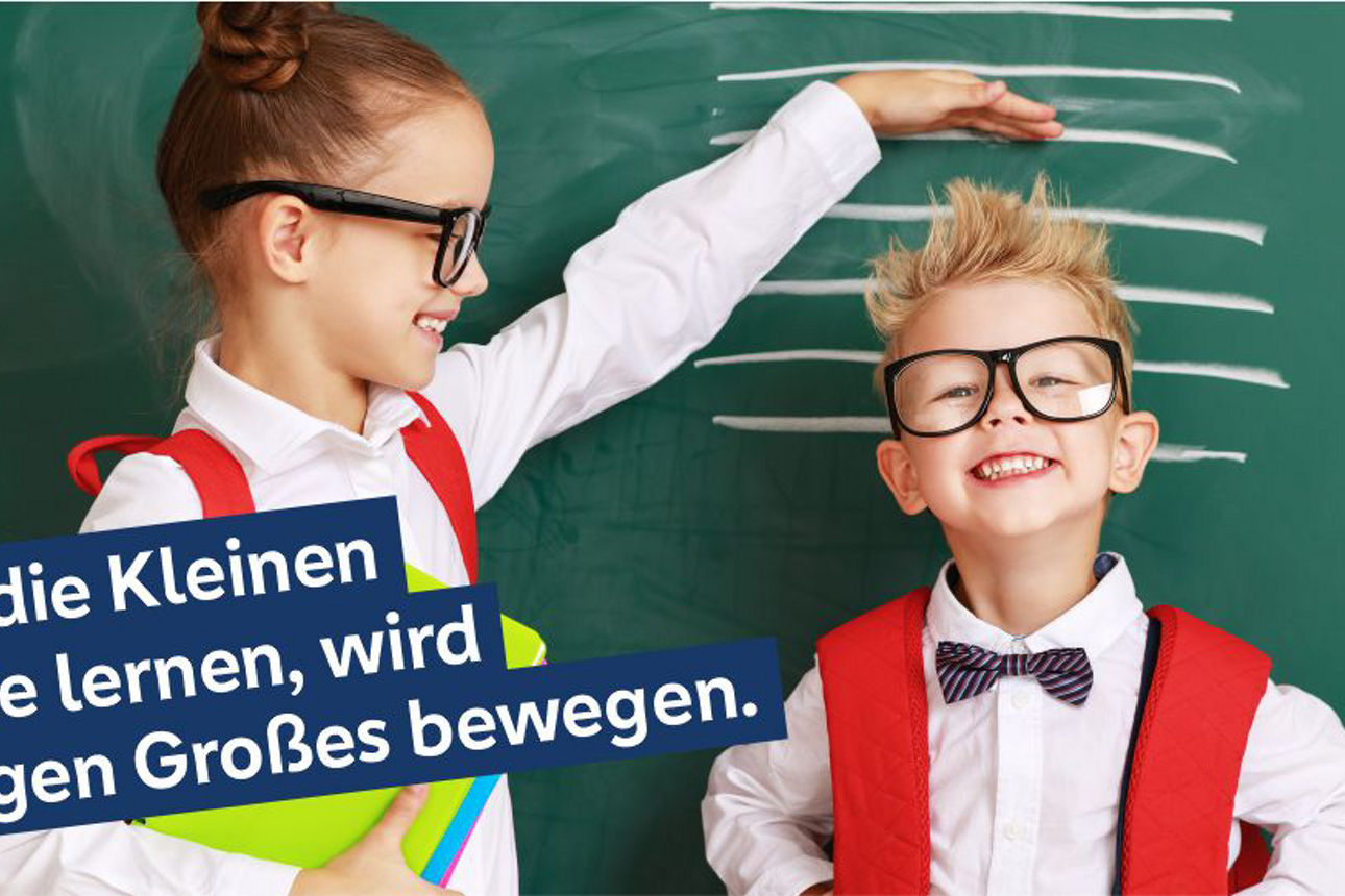 Zwei Kinder vor einer Schultafel, die ihre Größe mit Kreidestrichen messen.