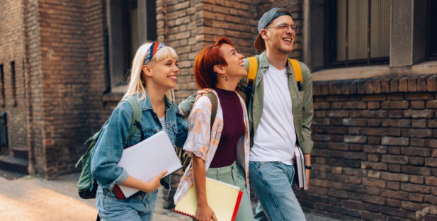 Drei Schüler laufen einen Geweg entlang