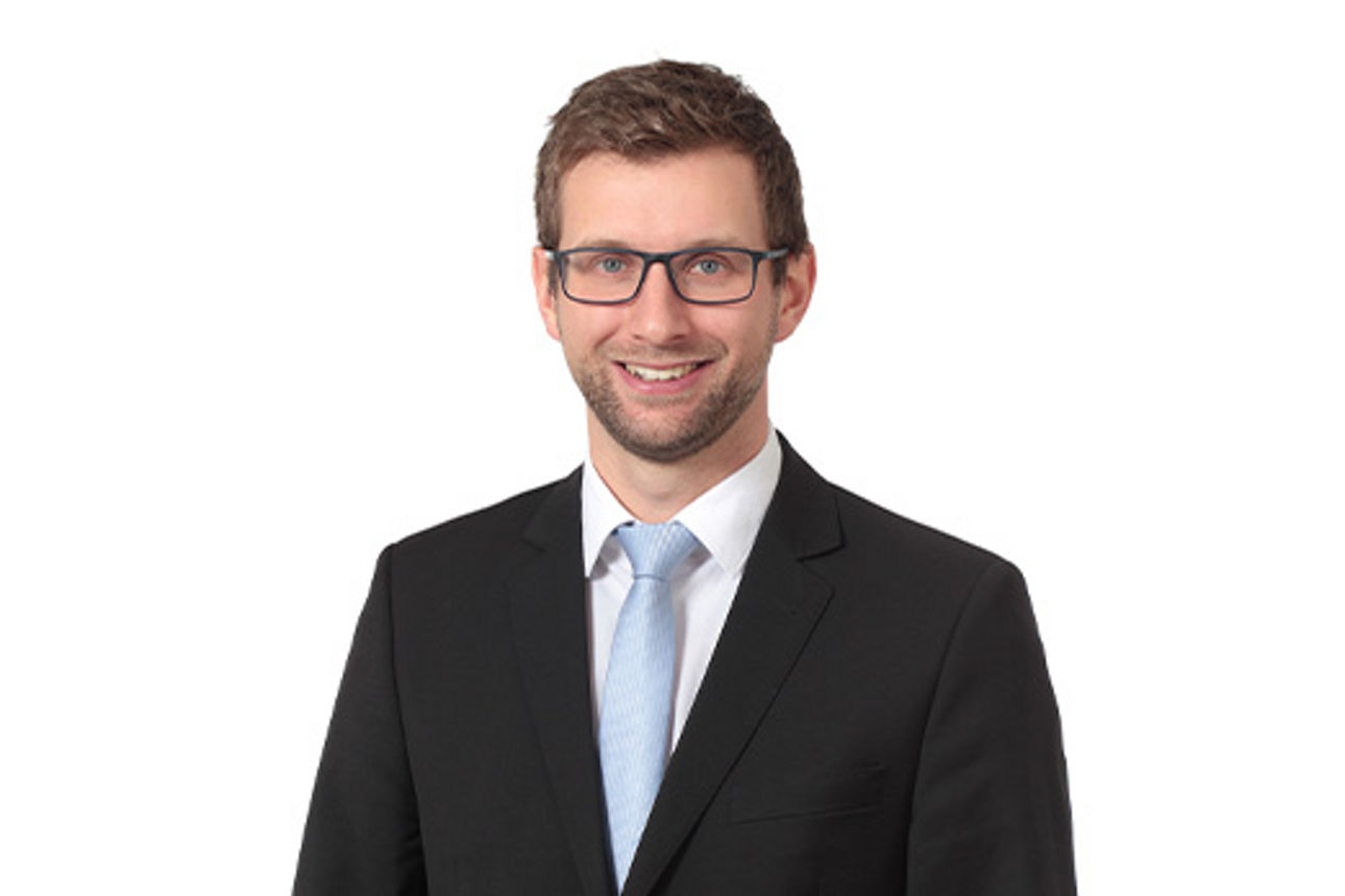 Freundlich lächelnder Mann im Anzug, unser Firmenkundenberater Sebastian Schweiger