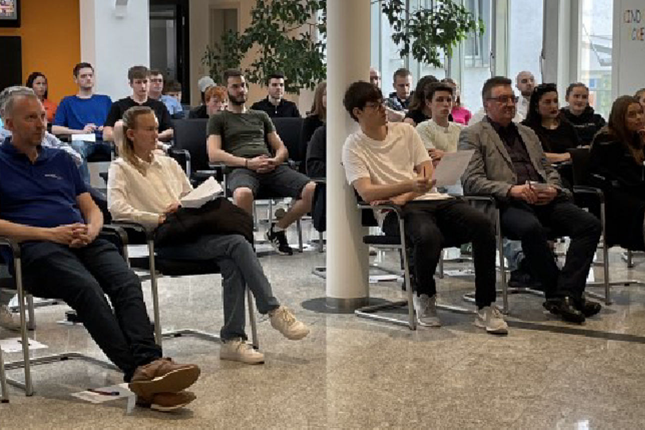 Eine Gruppe von Personen sitzt auf Stühlen und hört sich eine Präsentation an.