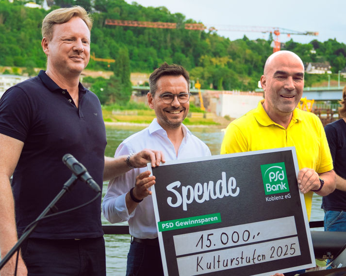Eine Gruppe Personen posiert mit einem Spendenscheck