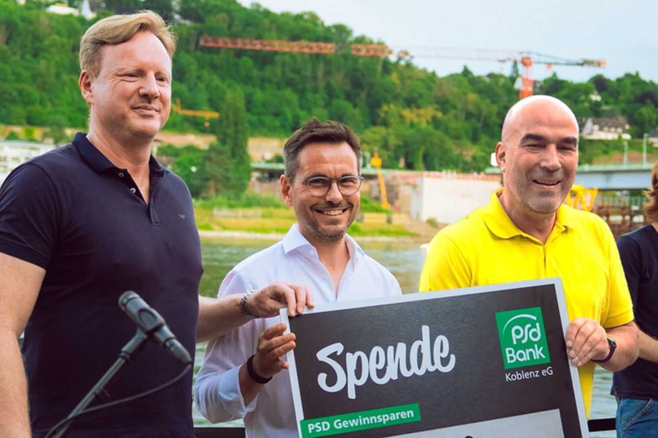 Eine Gruppe Personen posiert mit einem Spendenscheck