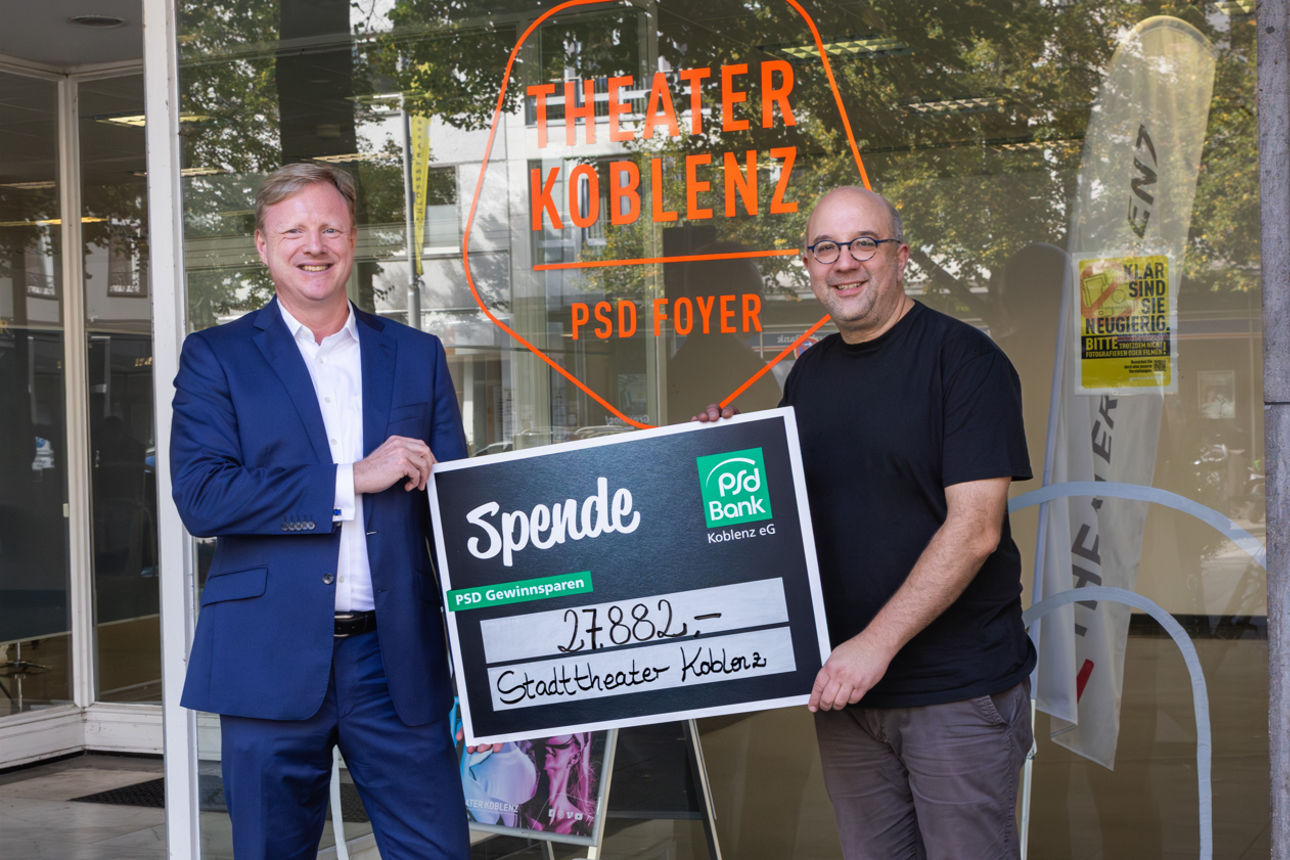 Eine Gruppe Personen posiert mit einem Spendenscheck