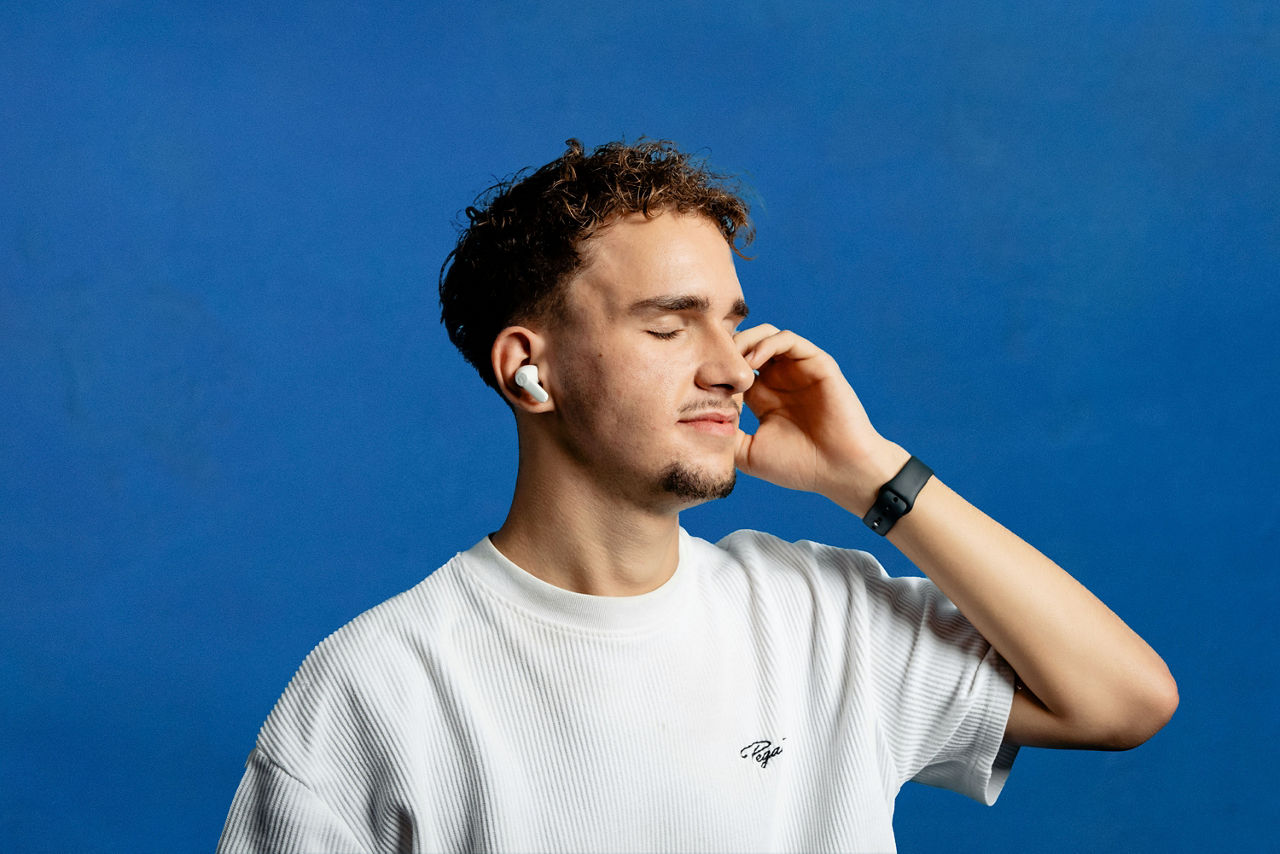 Mann hört mit geschlossenen Augen mit kabellosen Teufel Kopfhörern Musik.