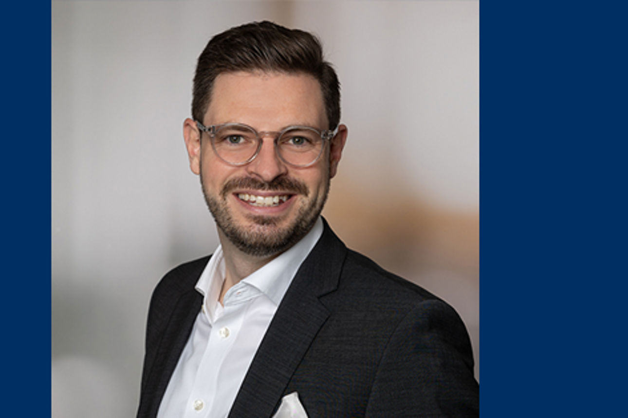 Zu sehen ist ein lächelnder Mann mit Brille 