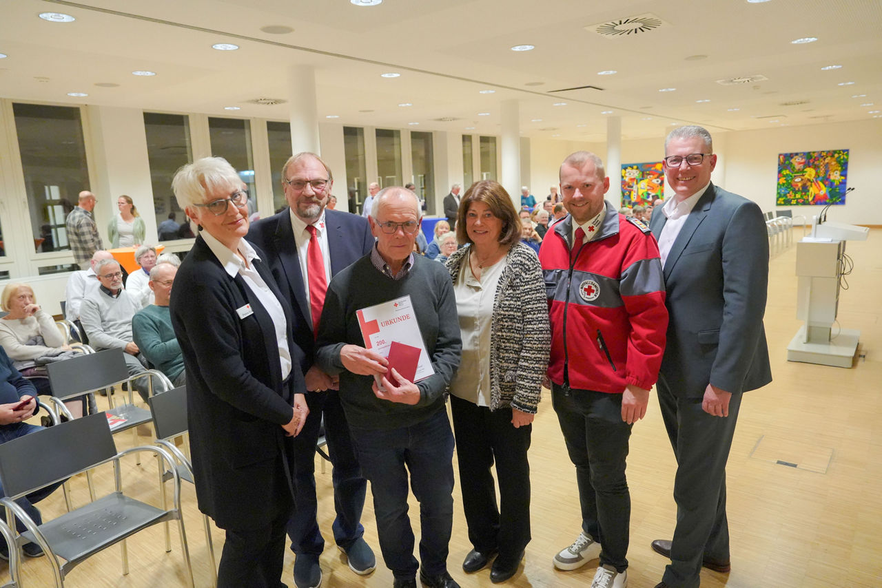 Sechs Personen stehen in einem hellen Raum mit Holzboden und großen Fenstern.