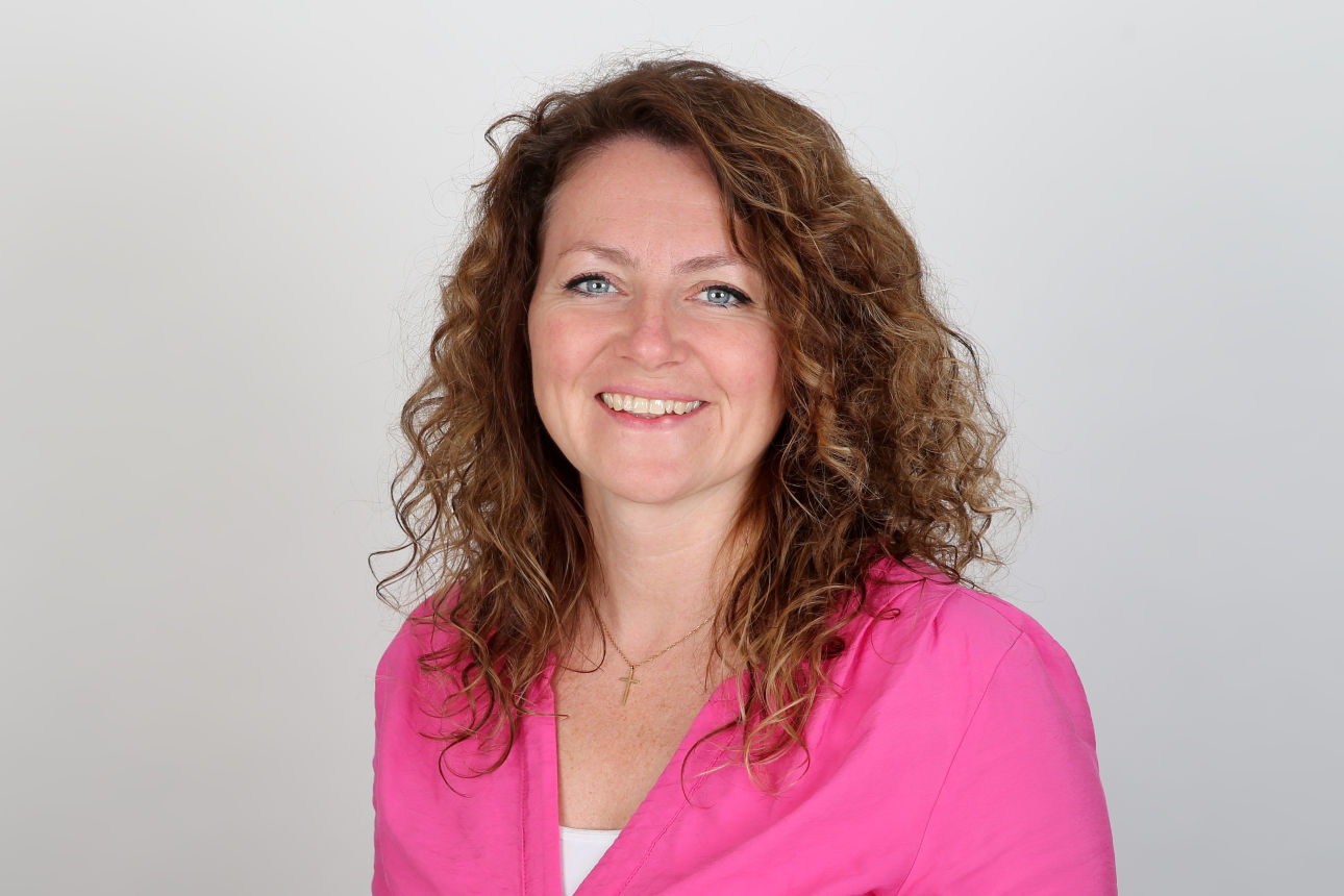 Eine lächelnde Frau schaut in die Kamera.