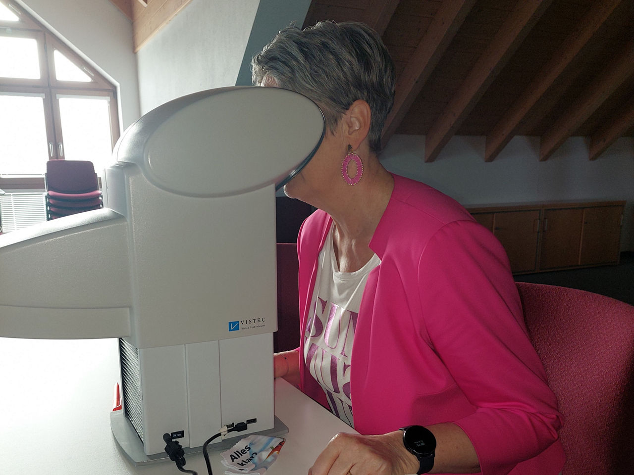 Mitarbeiterin beim Sehtest am Gerät.