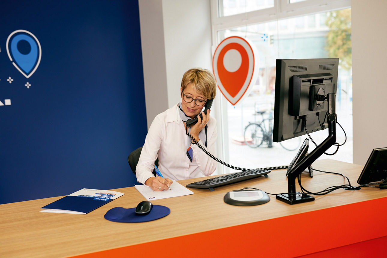 Eine Frau sitzt am Schreibtisch und telefoniert