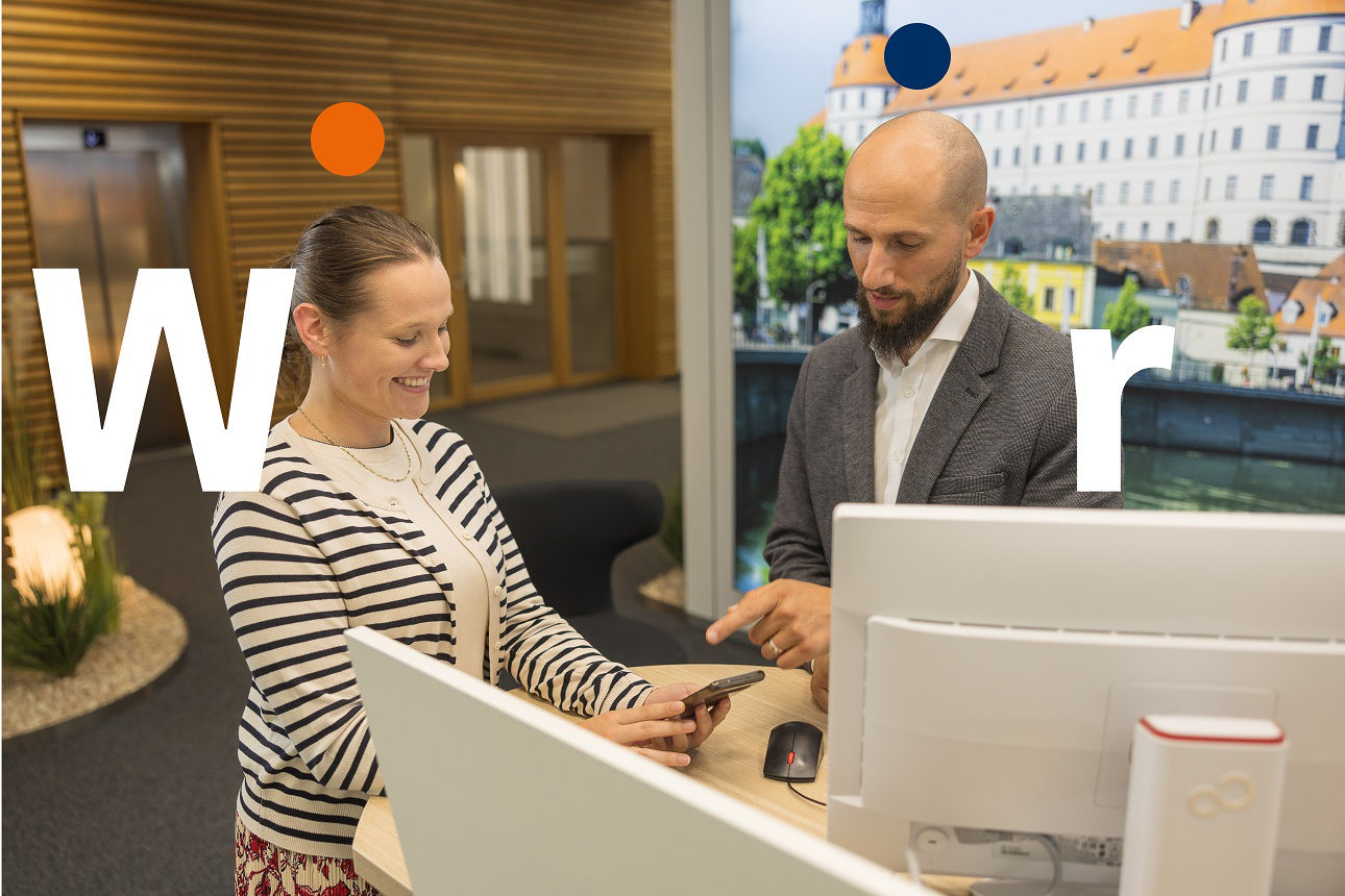 Zwei Personen ins Smartphone schauend an einem Service-Desk.