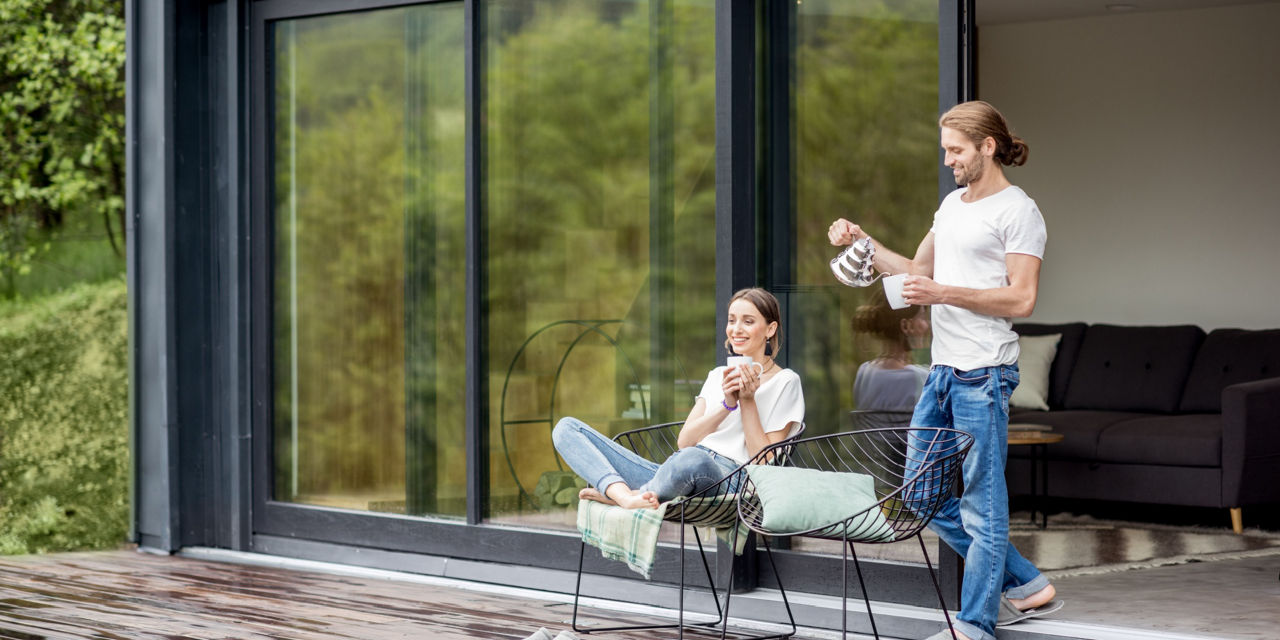 Ein Mann und eine Frau sitzend auf der Terrasse mit Kaffeetassen in den Händen