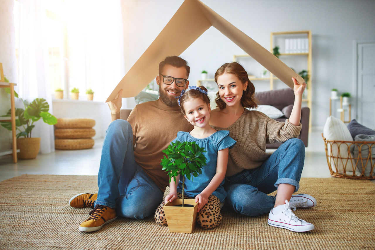 Eine Frau, ein Mann und ein Kind sitzen im Wohnzimmer und planen ein neues Haus