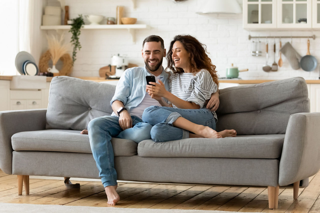 Frau und ein Mann sitzen auf der Couch und schauen sich die Banking App an