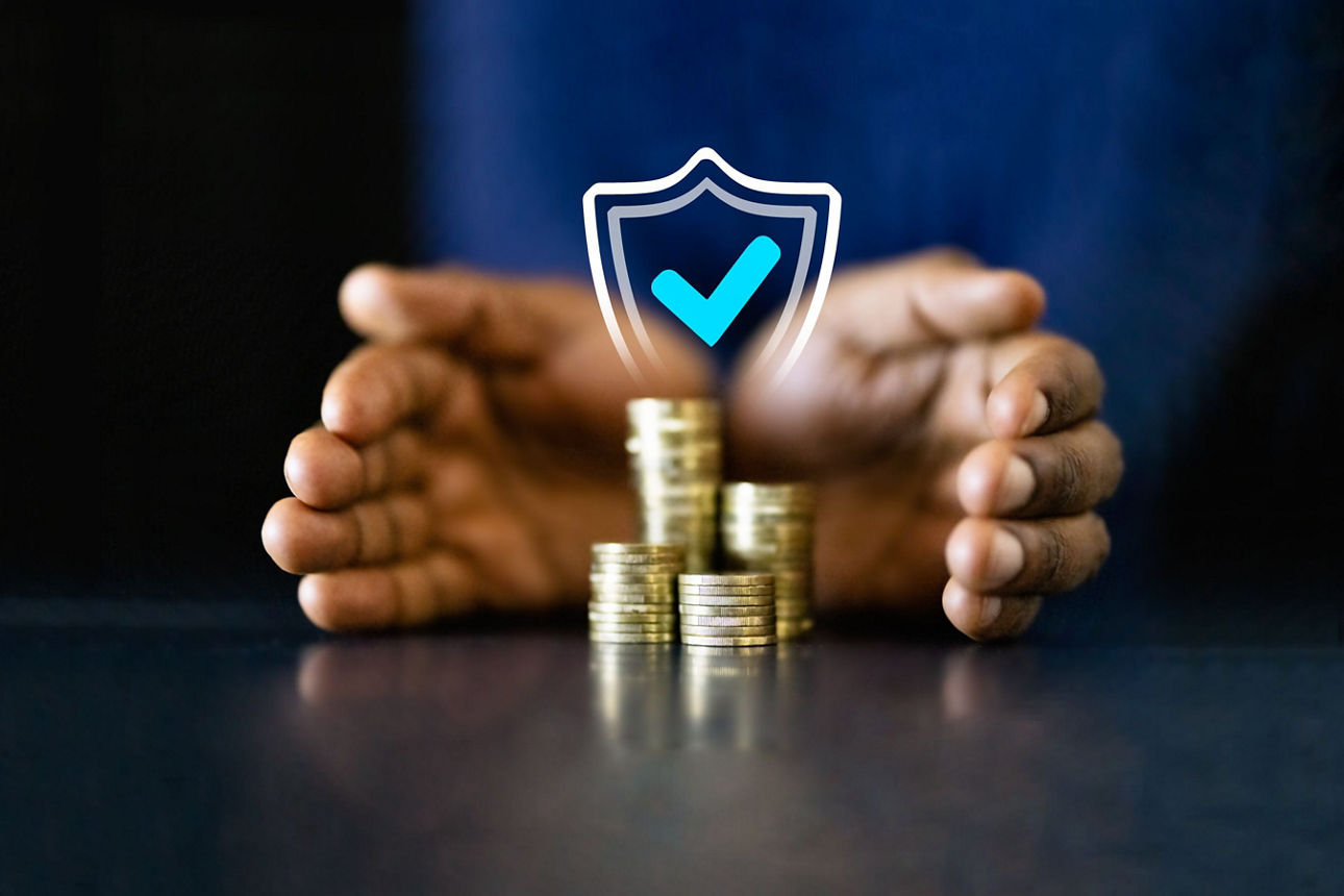 Hände sind schützend um Münzstapel gelegt