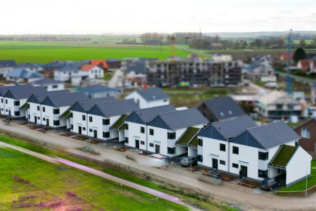 Luftaufnahme einer Reihe moderner Doppelhäuser mit Satteldächern.