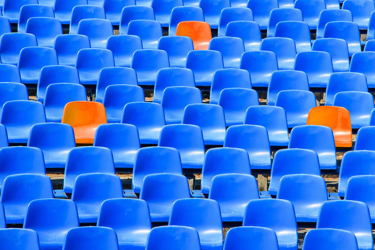 Viele blaue Sitze und dazwischen drei orangene