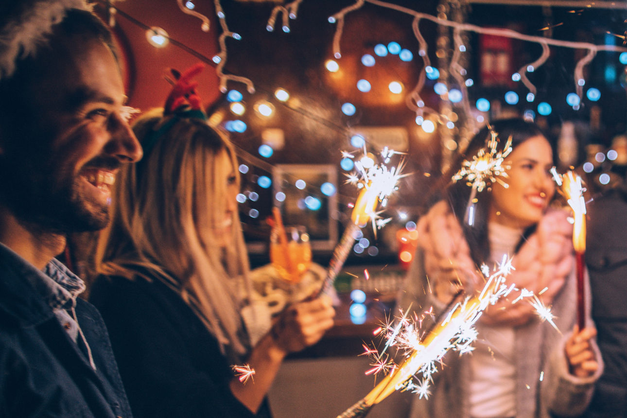 Mehrere Päärchen feiern zusammen Silvester mit Wunderkerzen in der Hand