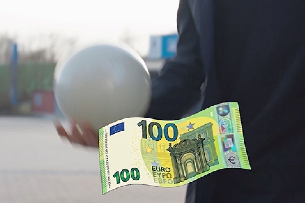 Ein hundert Euro Schein im Vordergrund zusehen wärend ein Mann ein Ball jongliert im Hintergrund.