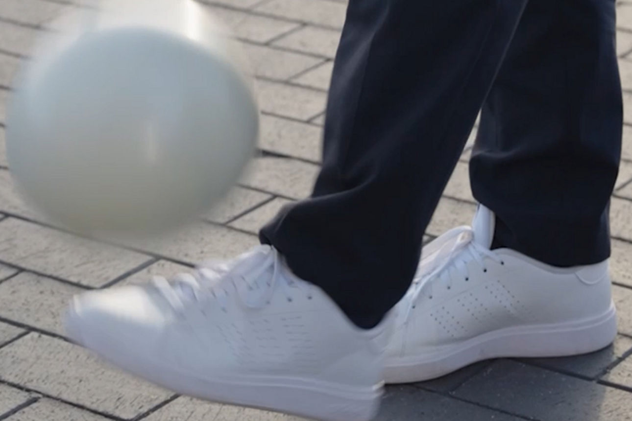Ein Fuß der ein weißen Ball jongliert. 