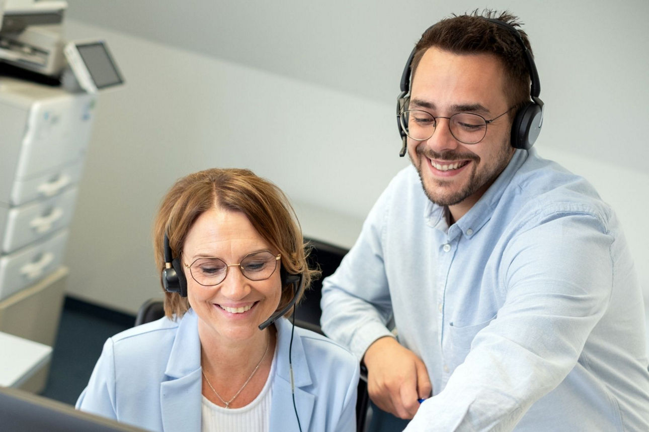 Ein Kollege zeigt seiner Kollegin etwas auf einem PC-Bildschirm.