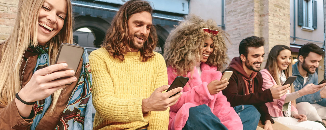 Junge Menschen auf Bank mit Smartphones